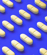 DENFOR 600 - SUPLEMENTO ALIMENTICIO Vitamina D2, magnesio, Zinc y Fósforo. Píldoras formadas en lineas de manera estética sobre fondo azul.