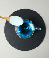 KARABELL COLÁGENO - SUPLEMENTO ALIMENTICIO. Imagen cenital de una tasa con liquido azul con una cuchara con polvo sobre esta.