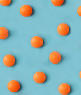 ZINOVID-C - SUPLEMENTO ALIMENTICIO. Comprimidos naranja sobre plano azul.