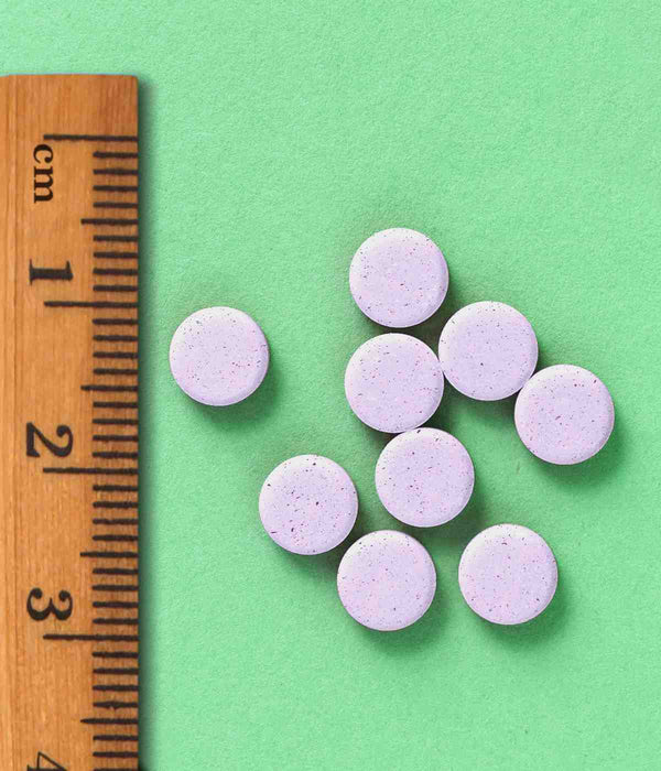 REDBELGY - MEDICAMENTO VITAMÍNICO. Muestras de las pastillas masticables sobre un fondo verde y una regla. 